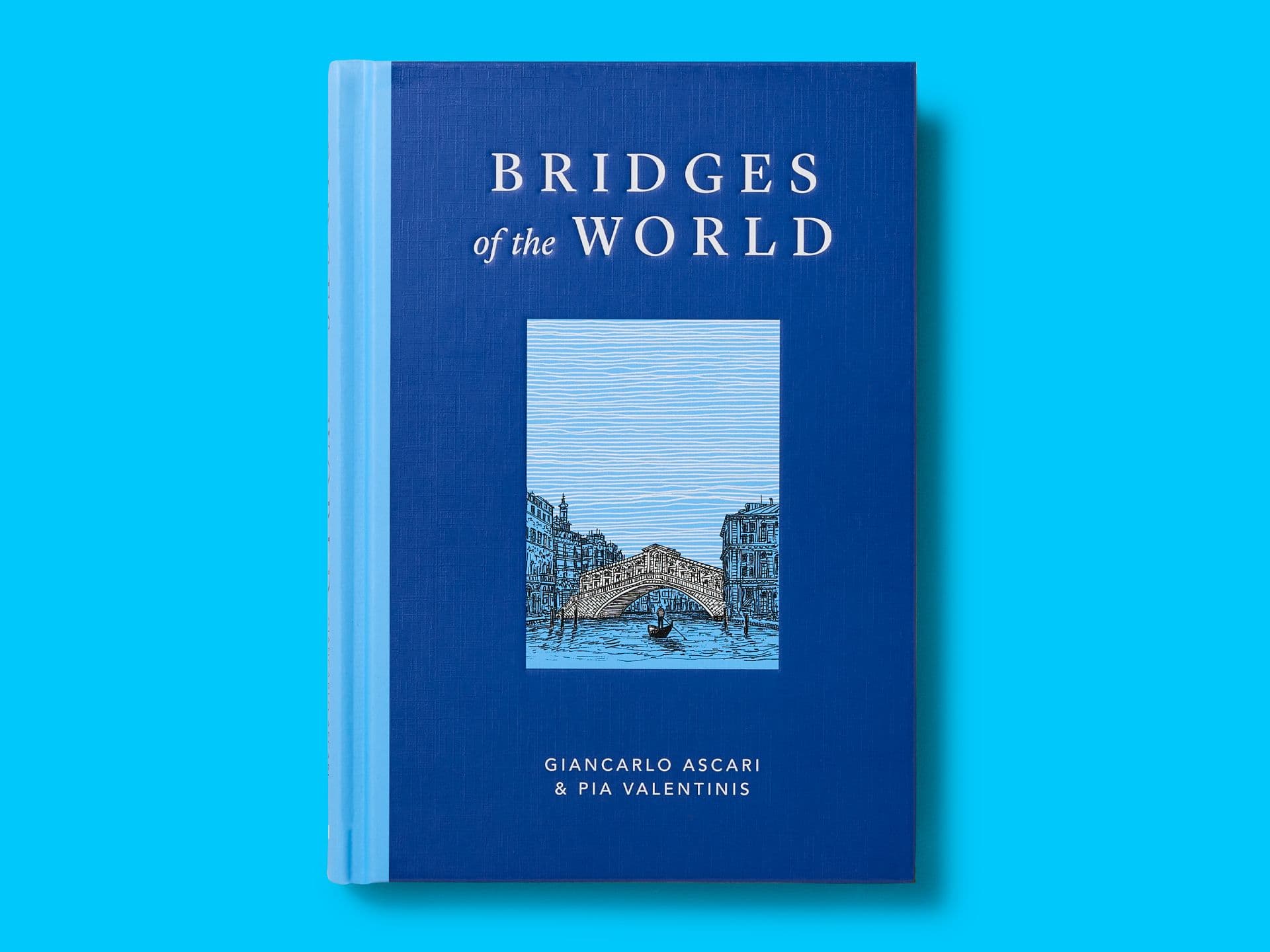 Book titled "Bridges of the World" on a bright cyan background, with a deep blue cloth-textured cover and a central illustrated panel of a stone bridge over water. Title appears in white serif type, with authors Giancarlo Ascari and Pia Valentinis listed at the bottom.