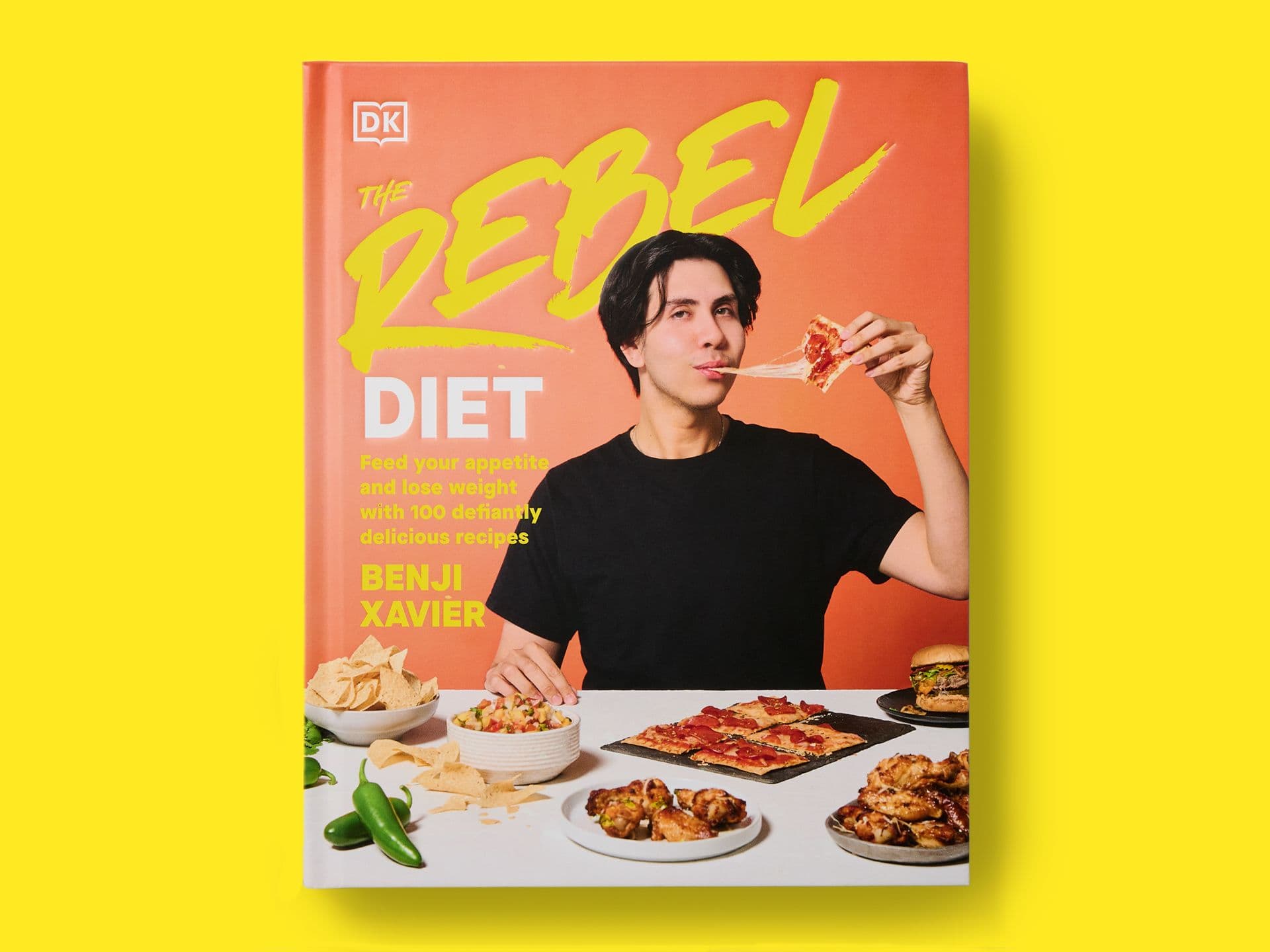 Bright orange book cover titled "The Rebel Diet" by Benji Xavier, featuring a portrait of the author eating a slice of pizza at a table of food including pizza, chicken wings, burgers, nachos, and chillies, with bold yellow typography and the DK logo, set against a yellow background.