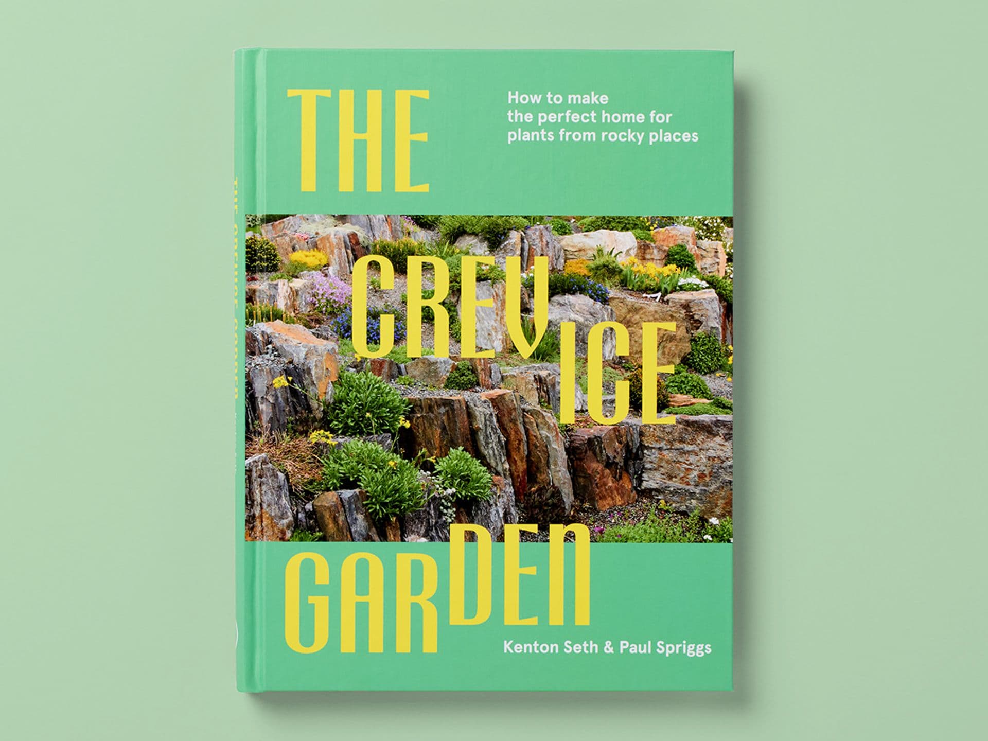 Green book cover titled "The Crevice Garden" by Kenton Seth and Paul Spriggs, featuring a photograph of plants growing among layered stone rocks, with the subtitle "How to make the perfect home for plants from rocky places," set against a pale green background.